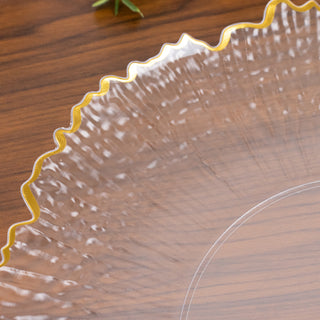 Clear disposable plate with a ruffled edge and gold trim.