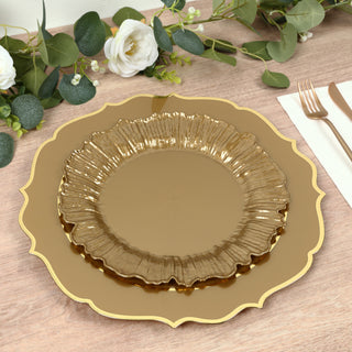 Gold decorative plates stacked on a wooden table with greenery and flowers.