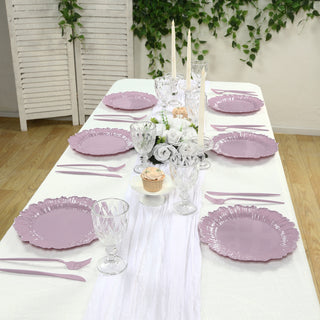 Elegant purple dinnerware set arranged on a table with candles and floral centerpiece.