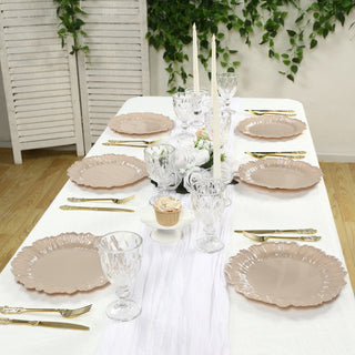 Elegant dining table set with blush plates, crystal glasses, and candles.