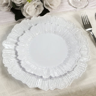 Two elegant white ruffled plates stacked on a table setting.