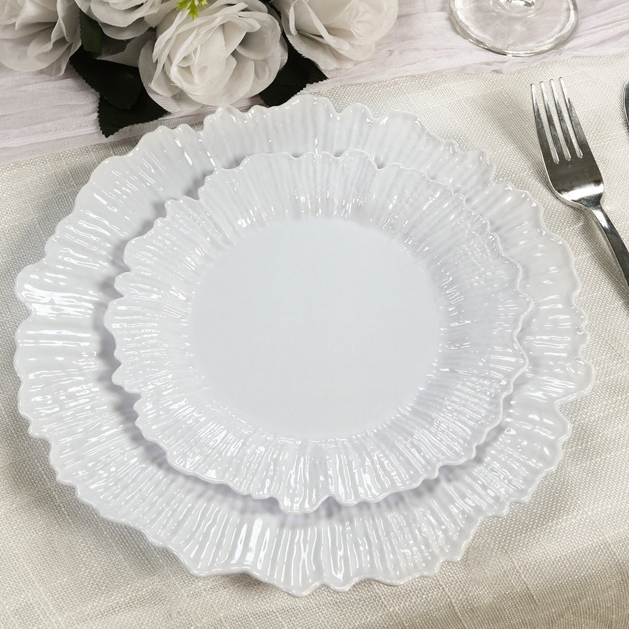 Two elegant white ruffled plates stacked on a table setting.