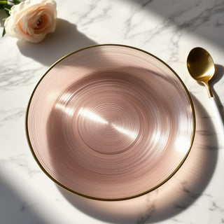 Pink spiral design plate with gold rim on marble surface.