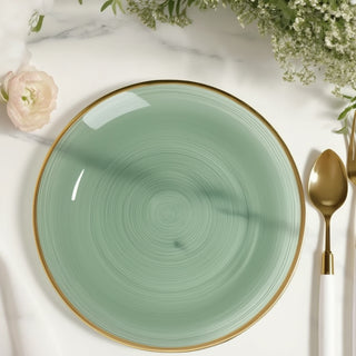 Green ceramic plate with gold rim on a marble surface.