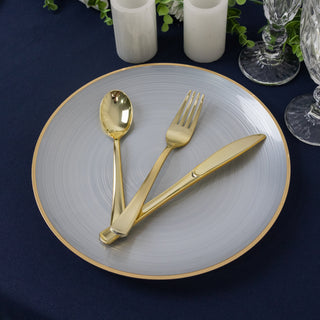 Elegant silver plate with gold cutlery set on a navy tablecloth.