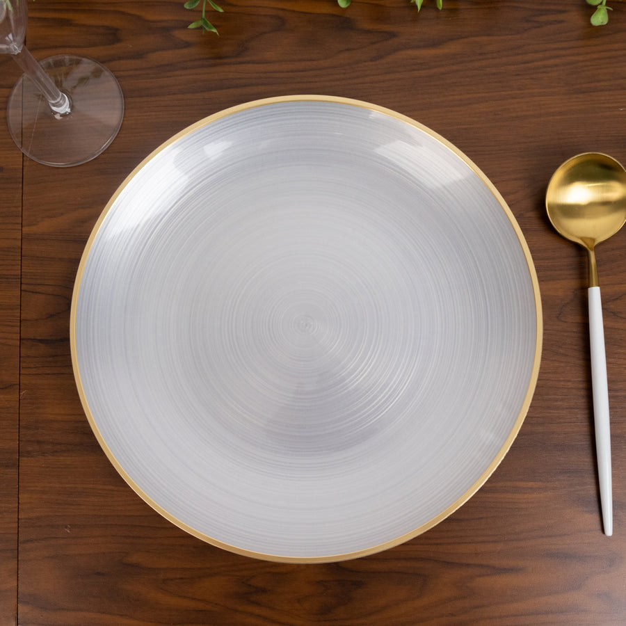 Elegant round plate with a silver swirl design and gold rim on a wooden table.