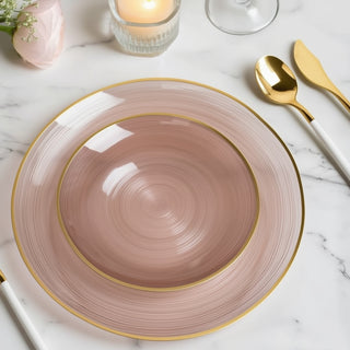 Elegant pink dinner plate with gold rim on a marble table setting.