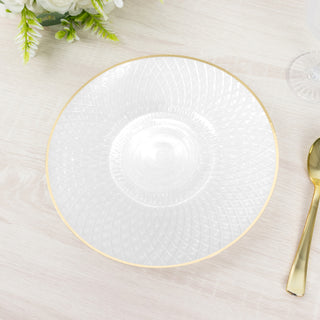 Decorative clear glass plate with gold rim on a wooden table.