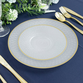 Elegant clear glass plate with intricate design and gold rim on a navy table setting.