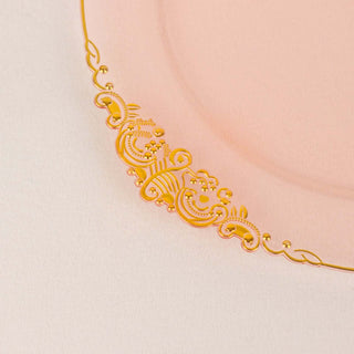 Gold decorative edge on a pink plate in a studio shot.