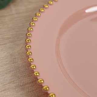 Pink plate with gold beaded rim on a wooden surface.