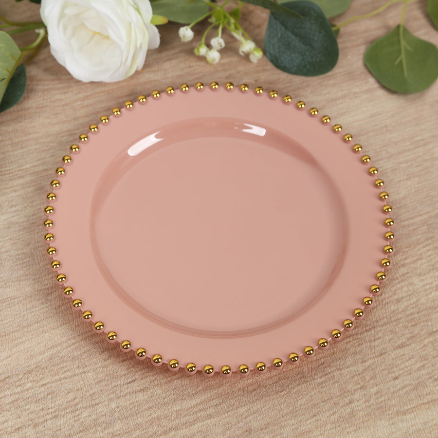 Pink plate with gold beaded rim on a textured surface.