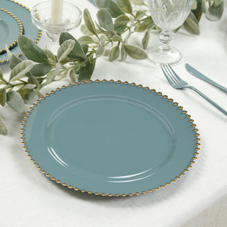 Teal decorative plate with gold trim on a dining table setting.