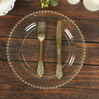 Elegant clear glass plate with gold fork and knife on wooden table.