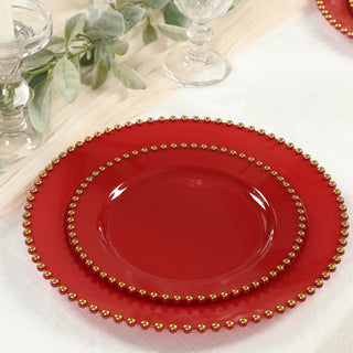Red decorative plates with gold beading on a styled table setting.