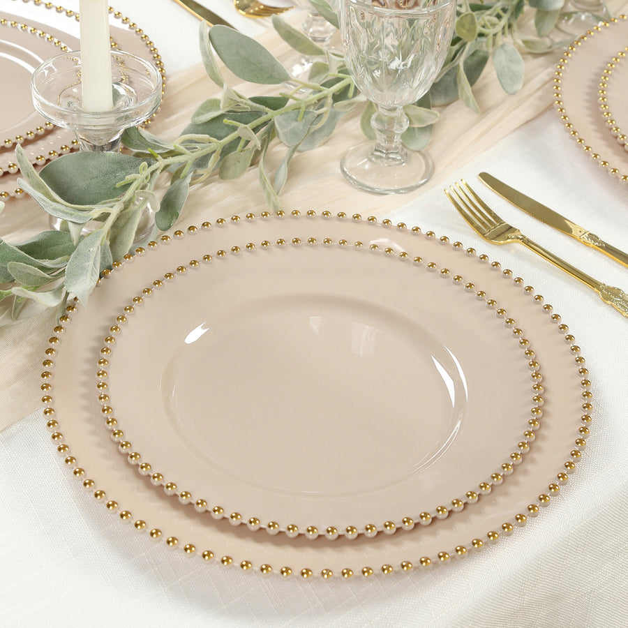 Elegant beige plates with gold bead trim arranged on a dining table.