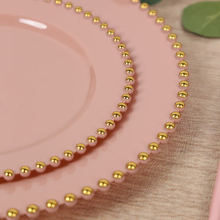 Pink decorative plates with gold beaded edges on a wooden surface.