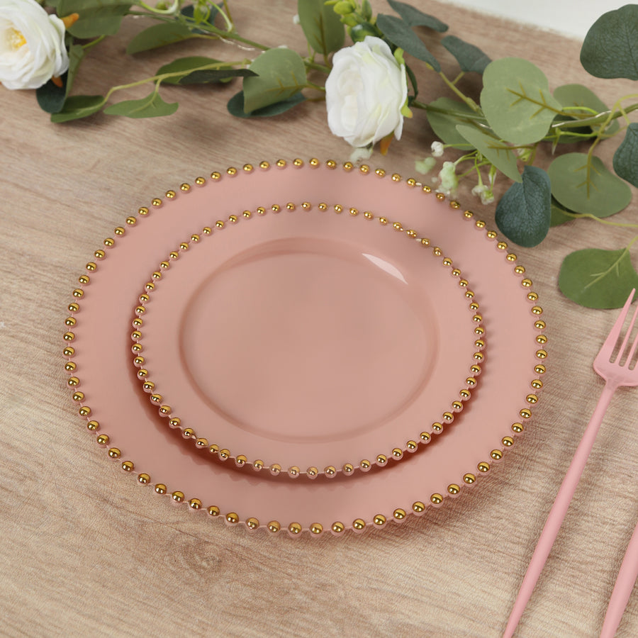 Pink plates with gold beaded rim on a wooden surface.