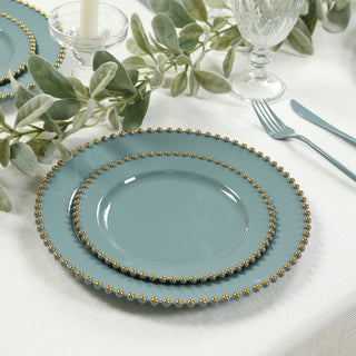 Elegant teal plates with gold beaded edges arranged on a textured tablecloth.