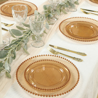Amber glass plates with beaded rims on a table setting with greenery.