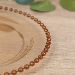 Brown beaded necklace on a wooden surface.
