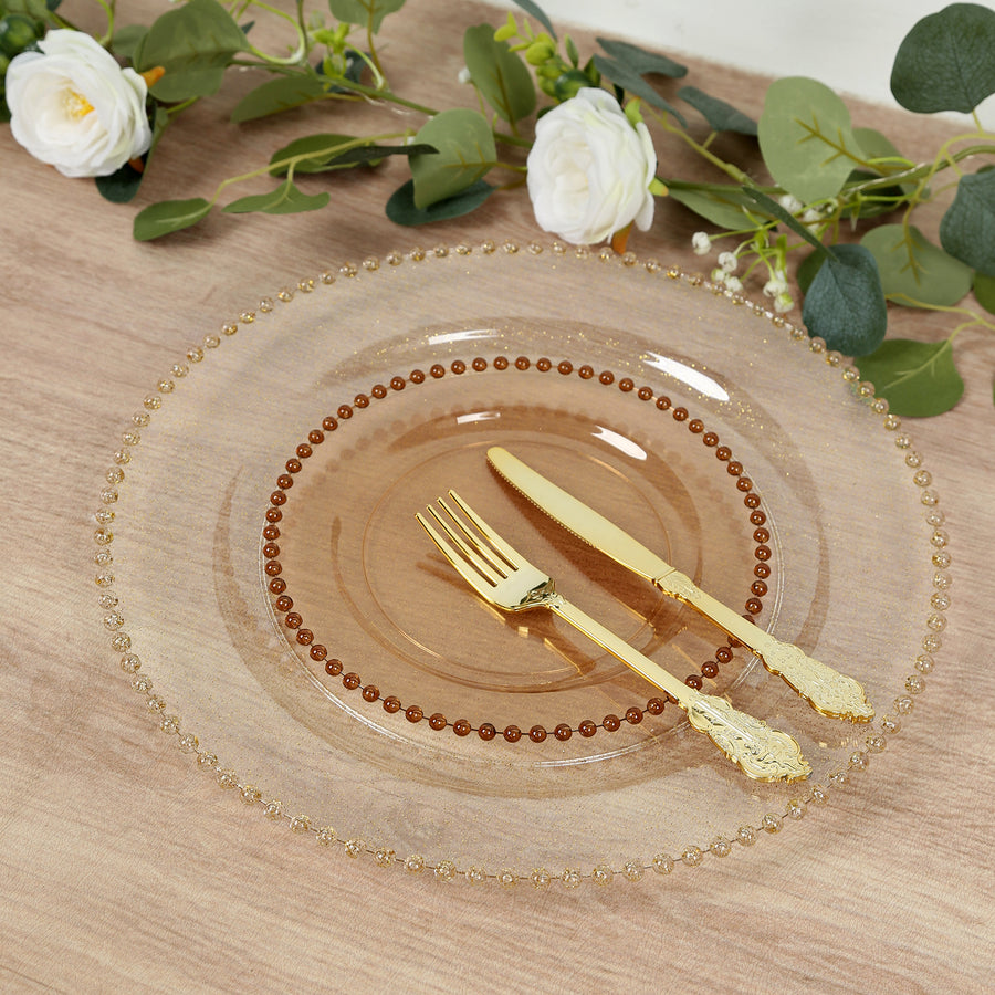 Elegant clear plate with gold beaded rim and golden cutlery on a decorative table setting.