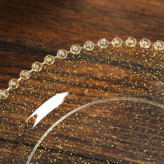 Clear glass plate with gold glitter accents on a wooden background.