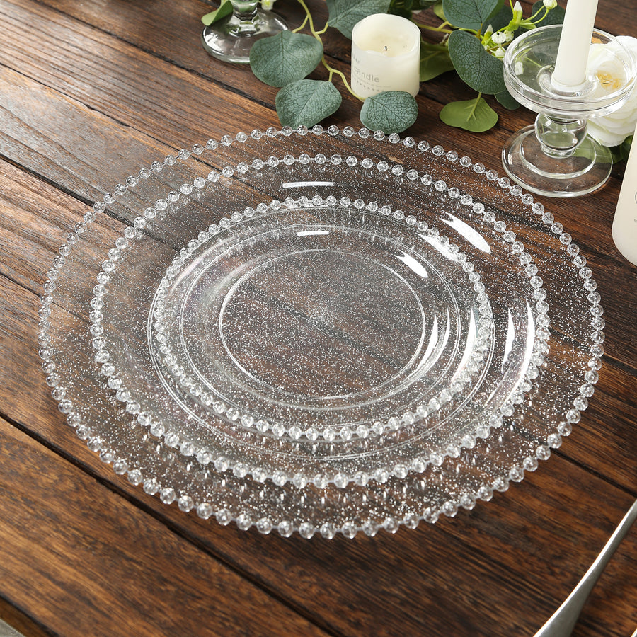 Clear decorative plates stacked on a rustic wooden table.