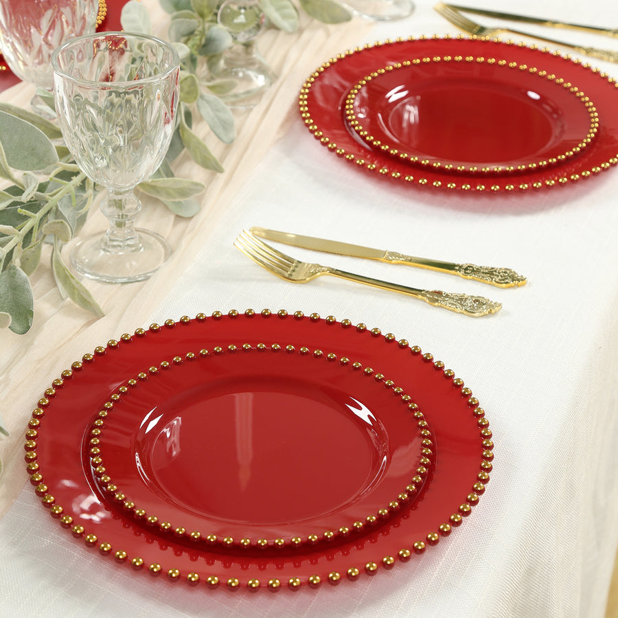 Red decorative plates with gold beaded trim on a dining table.