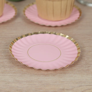 Pink decorative plate with gold trim on a wooden surface.