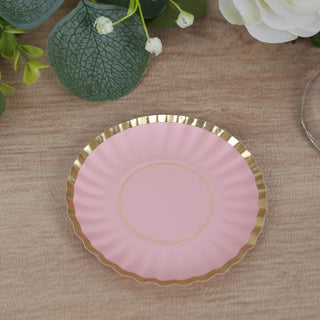Pink decorative plate with gold rim on a textured surface.