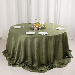 Round olive green tablecloth draping over a circular table with plates and decor.