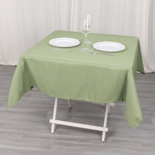 Green tablecloth set with white plates and cutlery on a folding table.