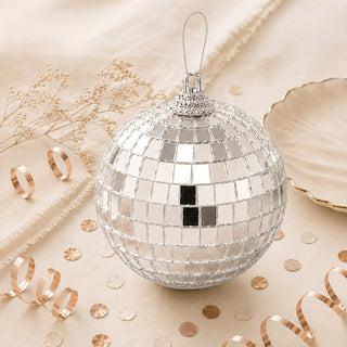 Silver disco ball Christmas ornament with mirrored tiles on a beige background