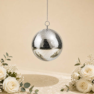 Silver disco ball hanging with white roses on a soft beige background