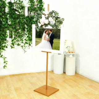 Wedding photo display stand with floral decoration in a styled setting.