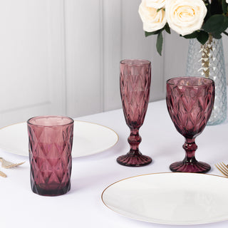 Set of elegant purple glassware on a dining table with floral arrangement.