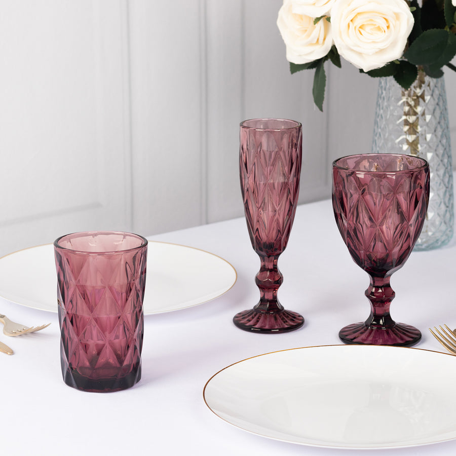 Set of elegant purple glassware on a dining table with floral arrangement.