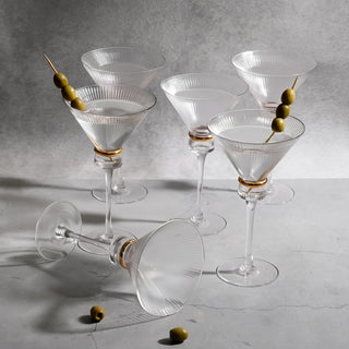 Elegant crystal martini glasses with olives on a gray background.