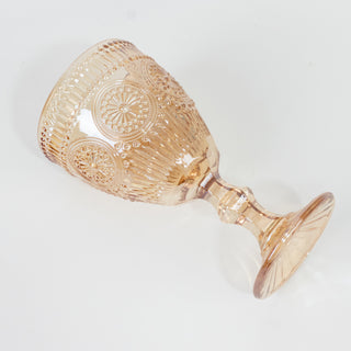 Rose-colored decorative glass goblet on a white background.