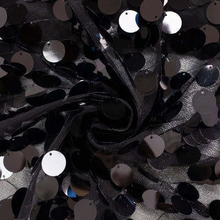 Black sequin fabric in a swirling pattern on a textured background.