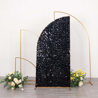 Black sequin backdrop with gold frame and floral arrangements.