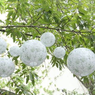 Decorative paper lanterns hanging among green leaves in a natural setting.