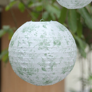 Decorative paper lantern with green floral pattern hanging outdoors.