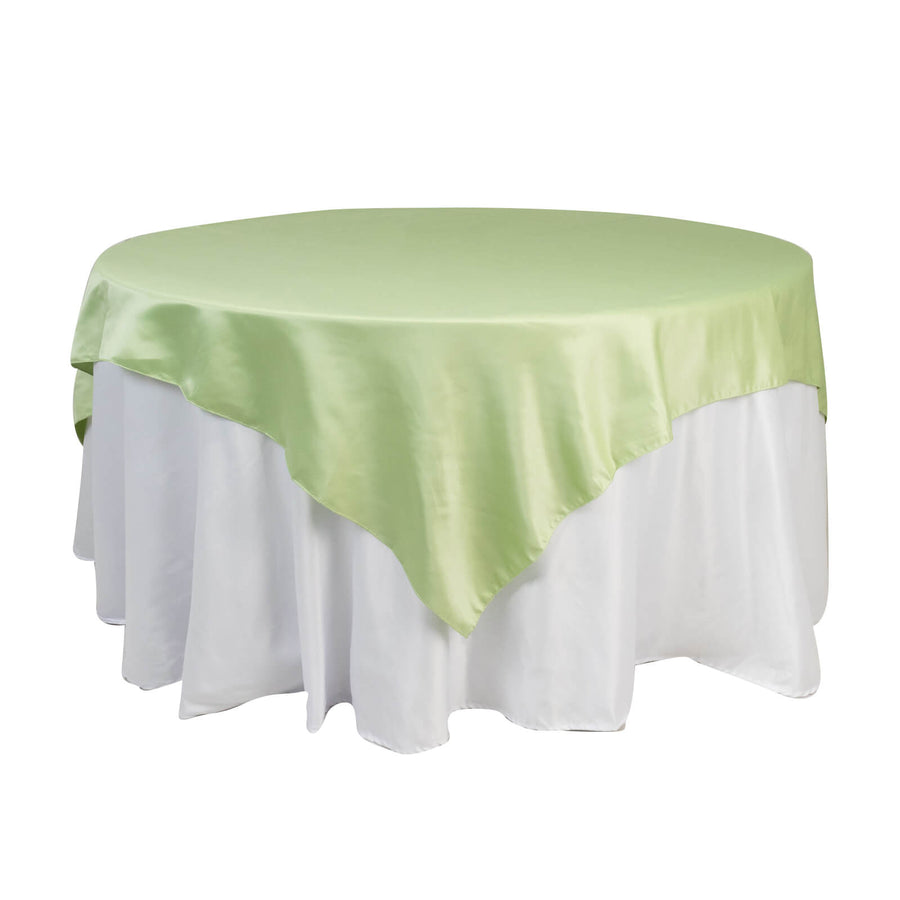 Round table with a light green satin tablecloth and white skirt