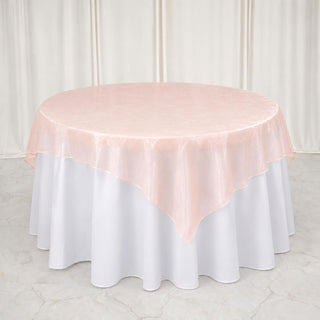 Round table with white tablecloth and blush pink overlay in elegant event setting