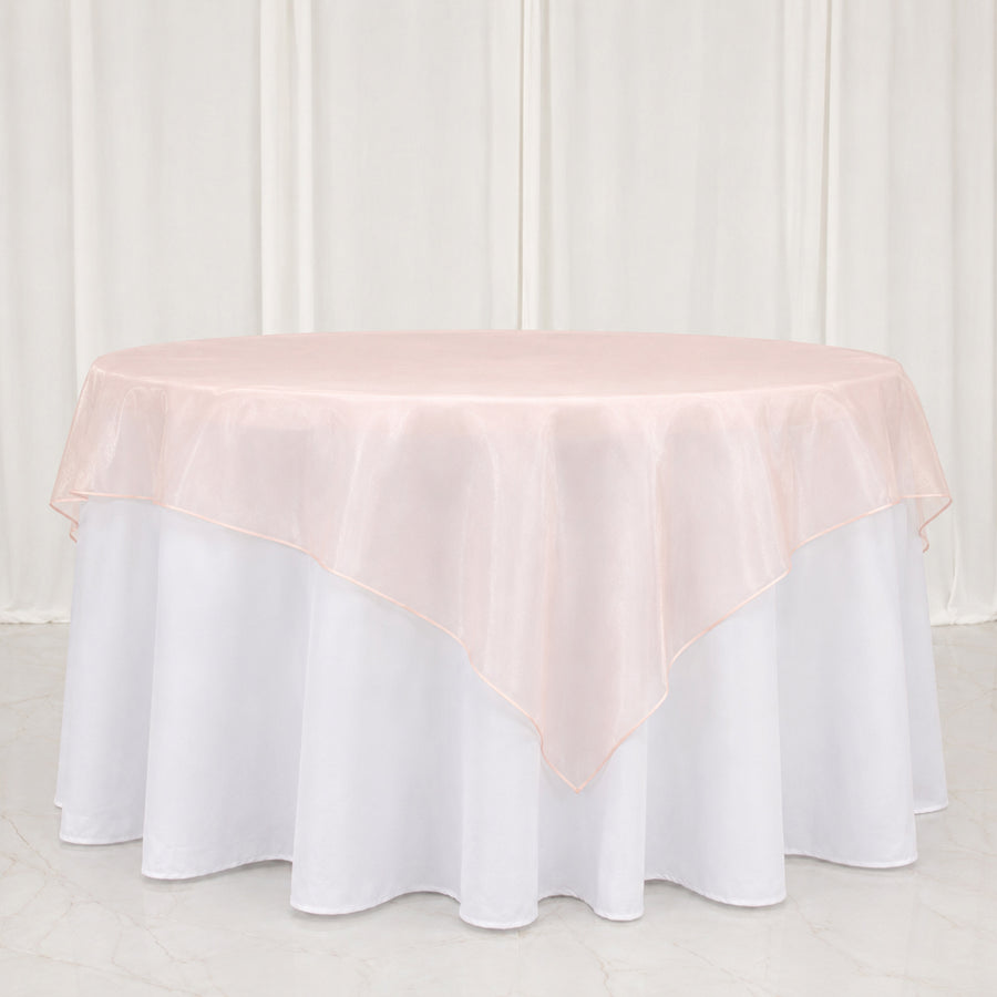 Round table with blush pink overlay and white floor-length tablecloth