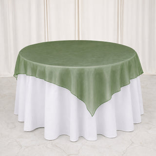 Round table with green sheer overlay and white tablecloth backdrop