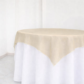 Beige tablecloth draped over a round table in a studio setting.