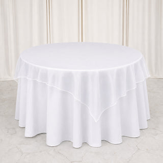 Round table with white layered tablecloth and elegant draped backdrop